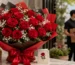 Luxurious bouquet of fresh red roses wrapped in premium paper with a satin ribbon, displayed in an elegant setting with a gift card and delivery backdrop, representing nationwide red rose bouquet delivery services across Pakistan.